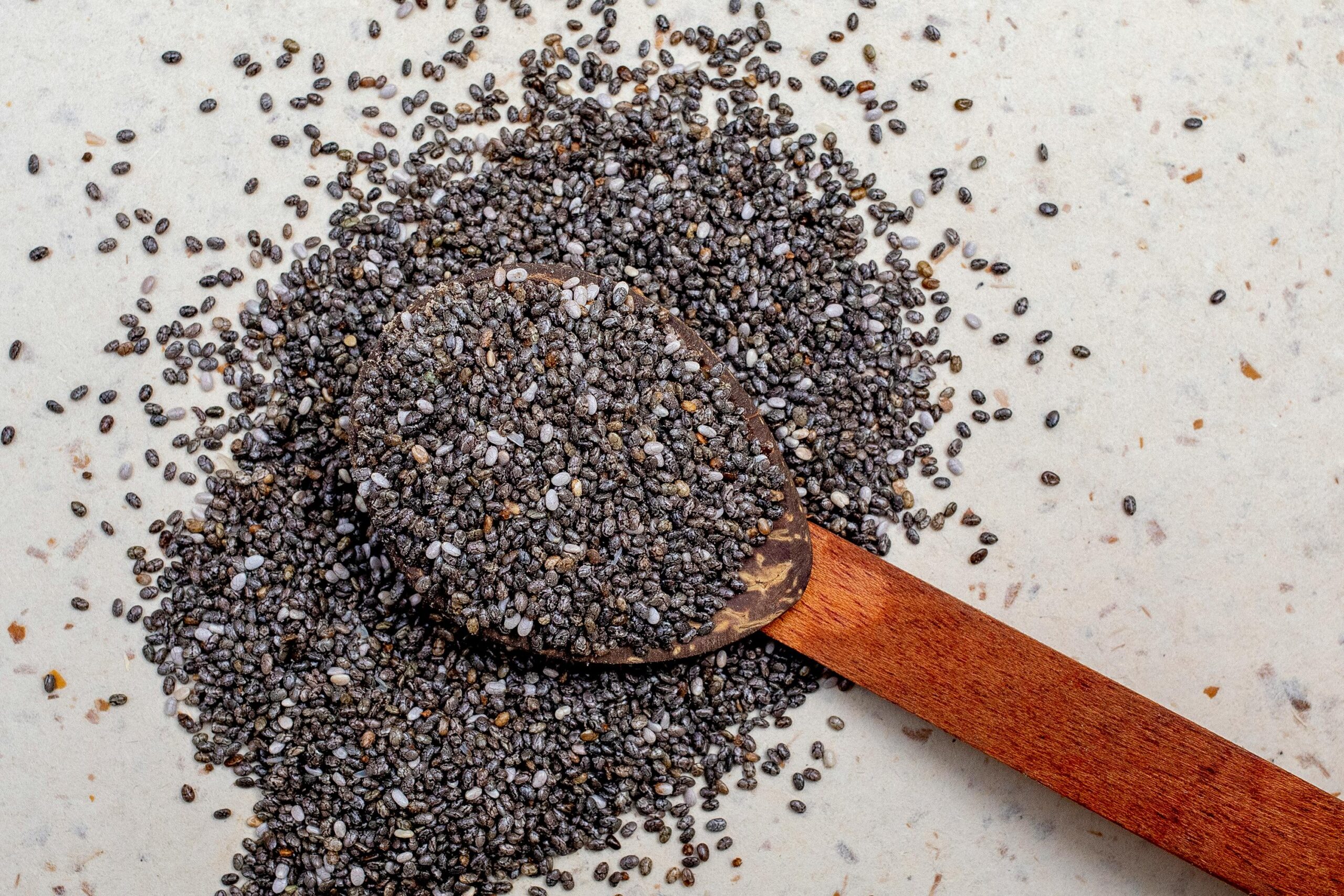 Wooden spoon filled with chia seeds, highlighting their texture and nutritional value.